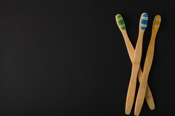 multiple bamboo toothbrush pile on black background