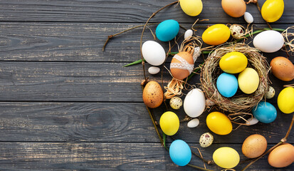 Blue and yellow colored Easter eggs and regular egg on wooden holiday banner, background, selective...