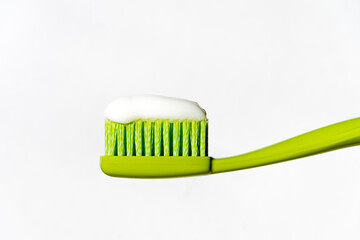 Green toothbrush with toothpaste on a white background. Isolated.