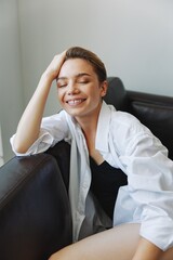 Women lying at home on the couch portrait with a short haircut in a white shirt, smile, depression in teenagers, home holiday