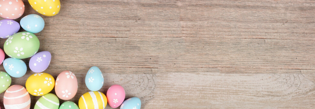 Colorful pastel Easter egg corner border. Overhead view on a light wood banner background. Copy space.