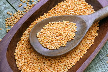 Pink lentil on wooden spoon and wooden platter