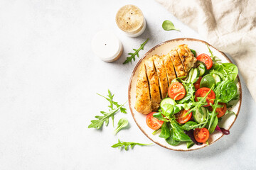 Fresh salad with chicken fillet and vegetables on white. Top view with copy space.