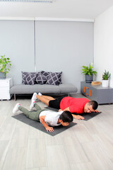 Overweight Latino dad and son exercise at home to lose weight and be healthy to avoid diseases such as diabetes or hypertension