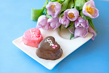 Heart-shaped cakes and tulip flowers on a blue background. festive background and mood. Valentine's day, romantic background