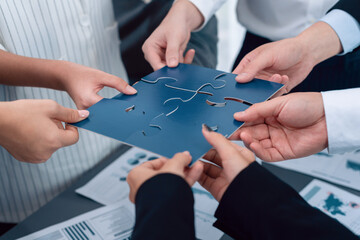 Closeup top view business team of office worker putting jigsaw puzzle together over table filled...