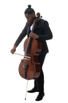 Full length portrait of a african american musician in a black suit and bow-tie playing a cello isolated on white background