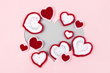 Heart symbol on a pink and gray background of knitted multicolored hearts. The concept of love. Flat lay