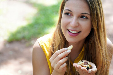 Close-up of healthy girl eating a mix of nuts seed dried fruits looking to the side outdoor on...