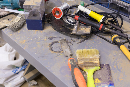 paintbrush soldering iron soldering wire spool on gray tabletop milling cutter wire brush chisel