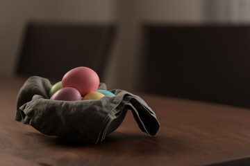 Easter eggs in a bowl with napkin on walnut wood table with copy space