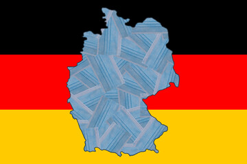 Obraz premium Randomly placed blue medical masks in the form of a geographical map of Germany against the background of the national flag of Germany