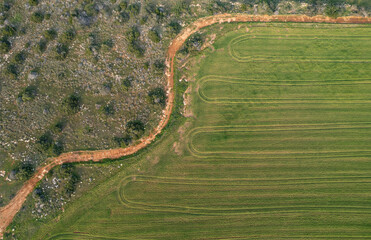 Drone aerial of curvy empty rural road ang green agriculture field. Farmland outdoor