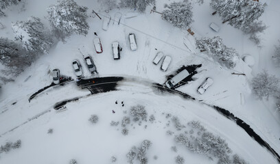 Drone scenery of car vehicles covered in snow on parked on a frozen road. Extreme weather snowstorm dangerous road. Troodos mountain Cyprus