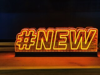 Yellow neon inscription New with hashtag. Illuminated information board. Modern sign for shop