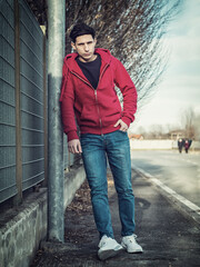 Attractive young man in city street leaning against pole
