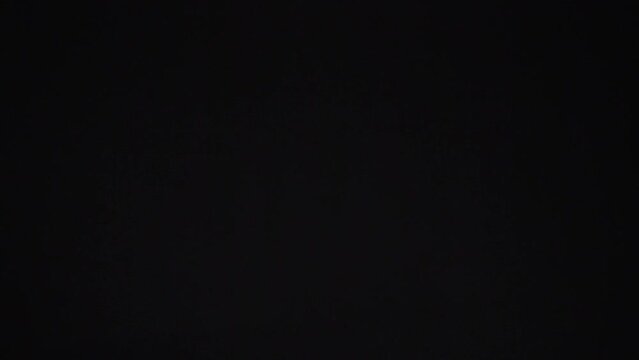 On a black background, a bitcoin gold coin is tossed and rotated, sparkling in different directions. Slow motion. Bitcoin coin flies beautifully in space on a black background.