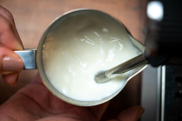 A barista froths or steams the milk to achieve a microfoam texture.