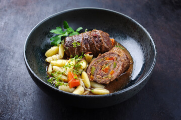 Traditionelle slow cooked deutsche Wagyu Rinderrouladen mit Gnocchetti-Sardi Nudeln in würziger Bratensoße als close-up auf einem Nordic Design Teller 