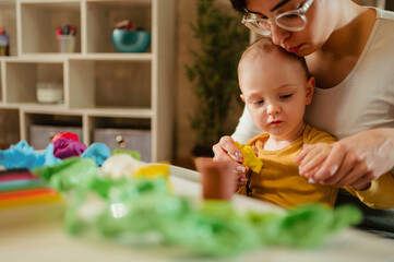 Fototapeta premium Mother and son playing with clay at home and creating art