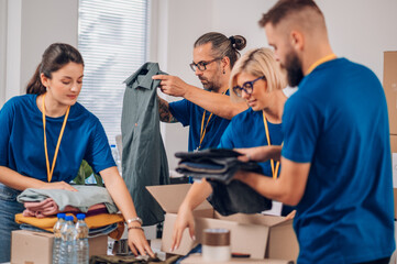 Diverse volunteers working in a charity donation center and packing clothes and food