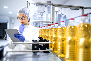 Food factory supervisor or worker holding digital tablet and thinking about production results inside refined vegetable oil production plant. - obrazy, fototapety, plakaty