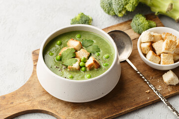 Green vegetable cream soup with pea, broccoli and croutons in ceramic bowl