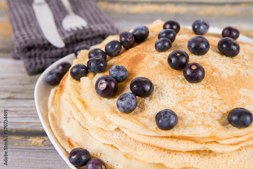 Sticker Pile of crepes with blueberry fruit on a wooden background