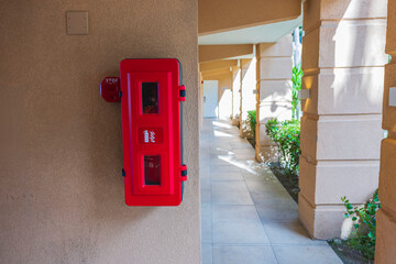 Close up view of fire extinguisher box with fire extinguisher and call button on hotel wall. Aruba.