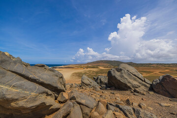 Fototapeta na wymiar Close-up view of large rocks in desert on Caribbean coast against blue sky with white clouds Aruba island.