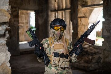 A woman in an army uniform holds a firearm in an abandoned building.