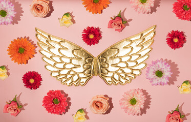 Angel wings and lots of flowers on a pink background. Minimal spring concept
