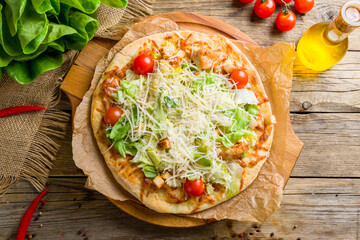 Pizza Caesar with chicken salad and tomatoes on board top view