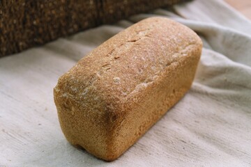 bread on the tablecloth. Home baked whole grain bread. Crusty sourdough loaf of wheat bread with wholegrain flour. fried bread crust. 