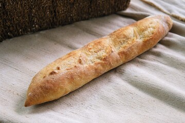 freshly baked baguette. bread on the tablecloth. Home baked whole grain bread. Crusty sourdough loaf of wheat bread with wholegrain flour. fried bread crust. 