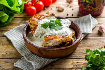chicken chkmeruli in Georgian on old wooden table