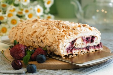 Meringue roll cake with cream, raspberries. Roulade, summer dessert. Confectionery, menu. Close up. Meringue roll with strawberries and grated chocolate. a piece of meringue roll in hand