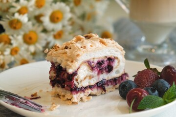 Meringue roll cake with cream, raspberries. Roulade, summer dessert. Confectionery, menu. Close up. Meringue roll with strawberries and grated chocolate. a piece of meringue roll in hand