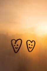 Foggy glass on sunset window with two drawn smile face heart shape concept photo