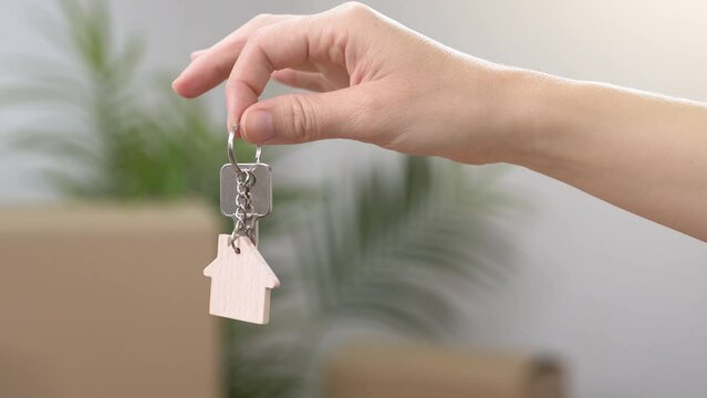 Handover of keys to new apartment, hand giving house shaped keyring. Concept of buying or rental