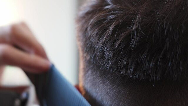 a man's haircut on his head in a barbershop. Close-up of a man cutting men's hair with clipper for haircut. Shortening of hair with the help of hairdressing clipper for haircut and combing.