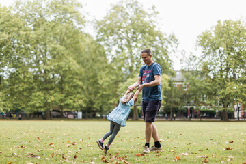 Little girl playing outside in park with her father