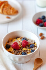 Breakfast bowl of oat flakes with berries, yoghurt and croissant