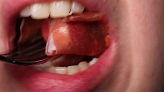 girl eats a slice of italian jamon. Close up eats a piece of Spanish of jamon