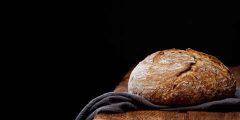 Wheat artisan sourdough bread on a wooden table black background. Panoramic view, free space for...