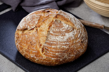 Round wheat rustic sourdough bread on a marble cutting board