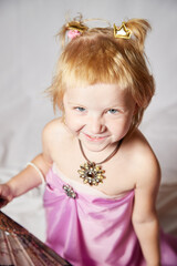 Portrait of cute kid girl posing in pink beautiful dress on a white background. Young female model looking as magic princess from fairy taly