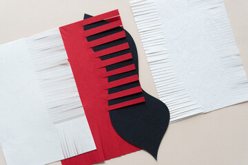 combined abstract white, red, and black paper shapes - some with fringe edges - on blank paper