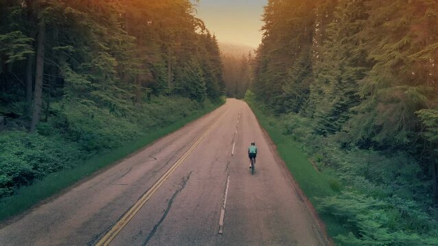 Man Cycles Up Road At Sunset, Endurance Concept