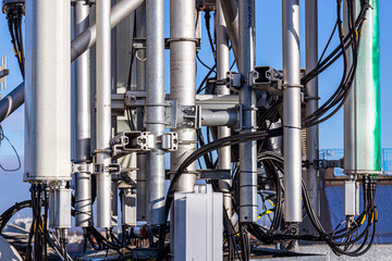 Close-up of a cellular antenna with many power cables, coaxial cables, optical fiber.
